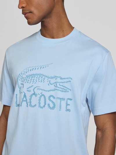 Männermodel trägt Regular Fit T-Shirt aus reiner Baumwolle von Lacoste in Hellblau mit Logo-Print, Nahaufnahme Oberkörper