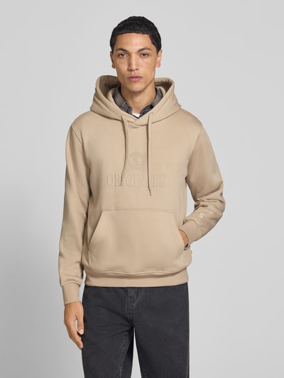 Männermodel trägt Hoodie aus Baumwoll-Mix Modell 'FREDERIKS' von JACK & JONES, beige Farbe, Label-Print, Ganzkörperansicht von vorne.