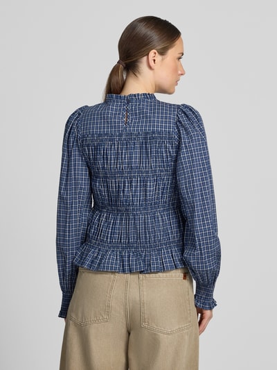 Männermodel trägt bluzka z bawełny Bluse mit Smok-Details und Rüschensaum Modell 'Marcia' von Neo Noir w niebieską kratkę, dopasowany krój, okrągły dekolt z falbanami, marszczenia, dół z obszyciem falbaną, długość tyłu 53 cm, długość rękawów 50 cm, Ganzkörperansicht Rückansicht