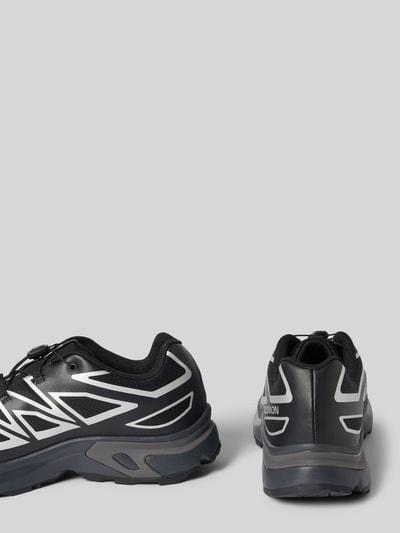 Produktfoto, Sneaker mit profilierter Sohle Modell 'XT-EVR' von Salomon in Schwarz mit abgerundeter Spitze und Logo, graue Details.