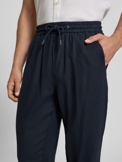 Männermodel trägt dunkelblaue Wide Fit Leinenhose mit Viskose-Anteil Modell 'Malvin' von Blend, elastischer Bund, Nahaufnahme Oberkörper, Leinen-Mix, Gesäßtasche und Tunnelzug, Kontext Herren Leinenhose.