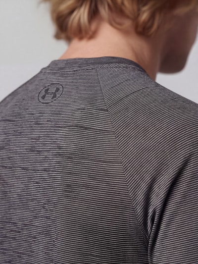 Männermodel trägt Regular Fit Sport-T-Shirt mit Logo-Print von Under Armour in Grau, feine Streifenstruktur, Nahaufnahme Oberkörper.