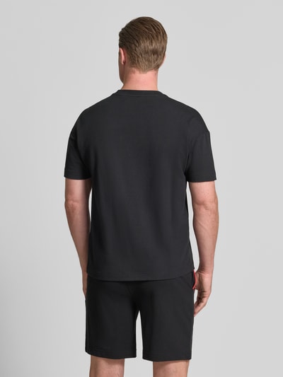Männermodel trägt Regular Fit T-Shirt aus Baumwoll-Mix Modell 'NOAH' von HUGO in Schwarz, glatte Oberfläche, Ganzkörperansicht Rückansicht. Herren T-Shirt von HUGO.