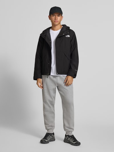 Männermodel trägt Jacke mit Label-Stitching Modell 'REIGN ON 2.0' von The North Face, schwarz, krój regular fit, Kapuze, Ganzkörperansicht von vorne