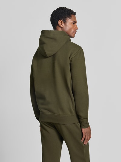 Männermodel trägt Regular Fit Hoodie aus Baumwoll-Mix von Polo Ralph Lauren in Olivgrün, glatte Textur, Ganzkörperansicht Rückansicht.