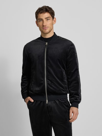 Männermodel trägt Sweatjacke mit gerippten Abschlüssen von Antony Morato in Schwarz, Relaxed-Fit, Stehkragen, Reißverschluss, Eingrifftaschen, Rückenlänge 65 cm, Ärmellänge 64 cm, Ganzkörperansicht von vorne.