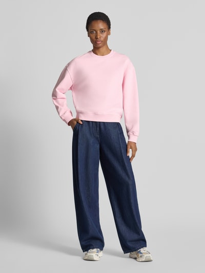 Frauenmodel trägt Relaxed Fit Sweatshirt aus reiner Baumwolle Modell 'Avan' von Samsøe Samsøe in Rosaton mit elastischen Abschlüssen, Ganzkörperansicht von vorne.
