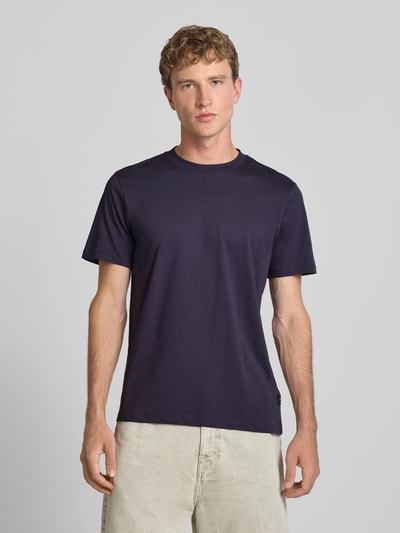 Männermodel trägt T-Shirt mit Rundhalsausschnitt und Logo von Replay aus reiner Baumwolle, Slim Fit, schlichtes Dunkelblau, Ganzkörperansicht von vorne.