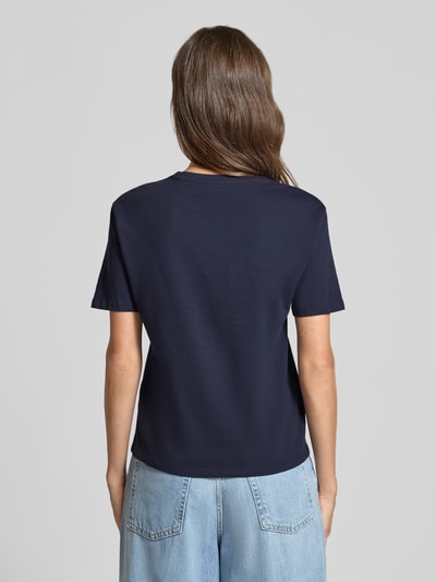 Frauenmodel trägt Regular Fit T-Shirt aus reiner Baumwolle mit Blumen-Applikation von Christian Berg Woman, dunkelblau, Kurzarm, Rückenlänge 54 cm, Ganzkörperansicht Rückansicht.