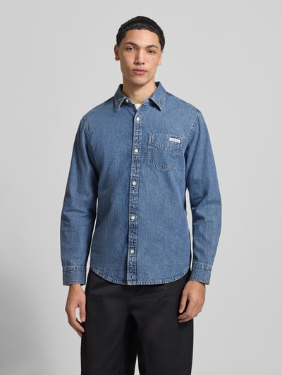 Männermodel trägt Regular Fit Jeanshemd mit Brusttasche und Label-Detail von Calvin Klein Jeans aus reiner Baumwolle, Ganzkörperansicht von vorne.