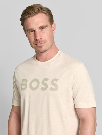 Męski model nosi Regular Fit T-Shirt aus reiner Baumwolle Modell 'TS_STRUCTURE LOGO 1027473' von BOSS Green w jasnym kolorze, gładka tekstura, duże logo z przodu, Nahaufnahme Oberkörper.