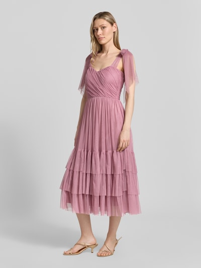 Frauenmodel trägt Knielanges Cocktailkleid im Stufen-Look von LACE & BEADS aus rosafarbenem Mesh, A-Linie, Drapierungen; Ganzkörperansicht von vorne. Rückenlänge bei Größe S: 104 cm, Brustweite: 40 cm.