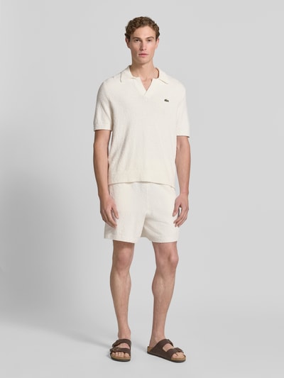 Männermodel trägt Regular Fit Poloshirt aus Baumwoll-Mix von Lacoste, Optik: Unifarben, Label-Patch, Bouclé, Ganzkörperansicht von vorne.