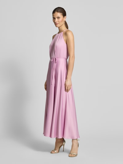 Modelka nosi Cocktailkleid aus Satin mit Bindegürtel von Jake*s Cocktail, różowy satynowy materiał, taliowana A-linia, długość pleców w rozmiarze 36: 130 cm, szerokość w rozmiarze 36: 40 cm, widok całej sylwetki z przodu.