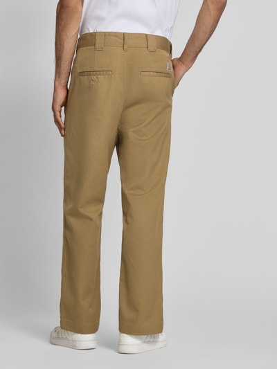Männermodel trägt Hose mit Gesäßtaschen Modell 'Denison' von Carhartt Work In Progress, Material-Mix, Relaxed-Fit, Farbe Beige, Ganzkörperansicht Rückansicht.