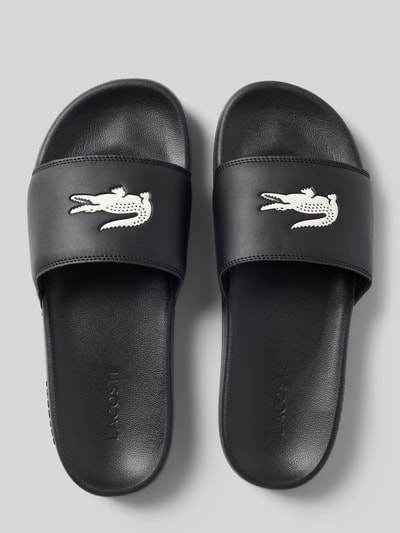 Produktfoto, Badeschuhe mit Logo Print Modell 'SERVE SLIDE' von Lacoste, Optik: Unifarben, Schuhspitze: Abgerundet, Absatzform: Flach, Applikation: Logo-Print, Verschluss: Schlupf/offen, Sohle: Strukturiert, Farbe Schwarz