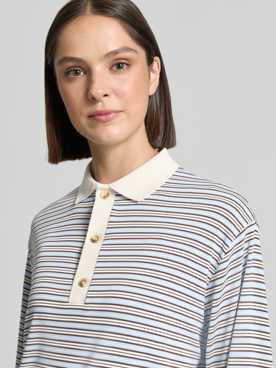 Frauenmodel trägt Relaxed Fit Poloshirt in langärmeligem Design von Neo Noir, Streifenmuster in Braun, Beige und Blau, Nahaufnahme Oberkörper, elastischer Material-Mix, Polokragen, Rückenlänge bei Größe 36: 62 cm.
