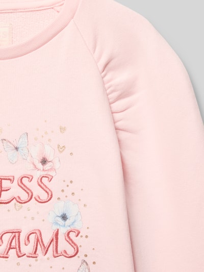 Mädchen trägt Sweatshirt mit Label-Detail von Guess in Rosa, reine Baumwolle, Rundhalsausschnitt, Nahaufnahme Oberkörper.
