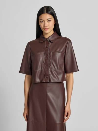 Frauenmodel trägt Cropped Bluse in Leder-Optik von VM by Vera Mont in Dunkelbraun mit Hemdblusenkragen und Knopfleiste, Ganzkörperansicht von vorne.