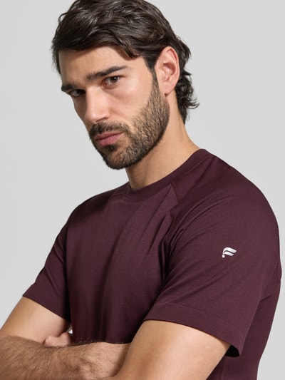 Männermodel trägt Slim Fit T-Shirt mit Logo-Print Modell 'Training Day' von Fabletics in Burgunder, Nahaufnahme Oberkörper, Herren T-Shirt, Rundhalsausschnitt, Rückenlänge bei Größe M: 71 cm.