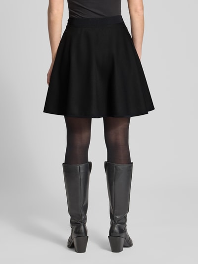 Frauenmodel trägt ausgestellten Mini-Rock aus Viskose-Mix Modell 'VETIRA' von BOSS, unifarben, elastischer Bund, Frill-Saum, Ganzkörperansicht Rückansicht.