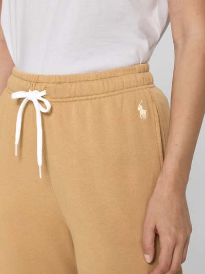 Vrouwenmodel draagt Regular Fit Sweathose uit katoenmix van Polo Ralph Lauren in lichtbruin met wit logo, detailopname heup.