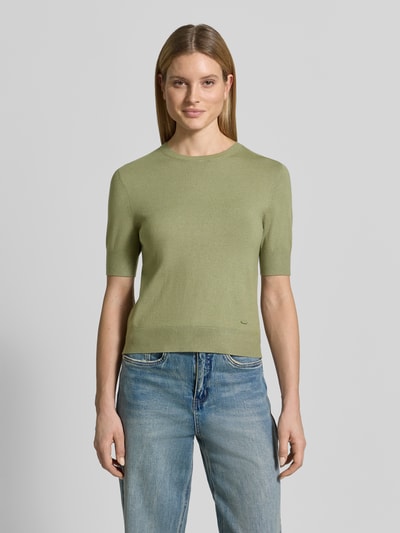 Kobiece modelka nosi Slim Fit T-Shirt aus Viskose-Mix od s.Oliver RED LABEL w imitacji dzianiny, krój slim fit, aplikacja z metką, okrągły dekolt, krótki rękaw, zakończenia prążkowane, drobny splot, mieszanka wiskozy, jasny zielony, prosty fason, tekstura gładka, z przodu, całe ciało, zdjęcie na wprost.