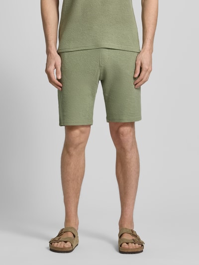 Männermodel trägt Sweatshorts mit elastischem Bund von MCNEAL in Grün mit Strukturmuster, Eingriffstaschen, Gerade Passform, Ganzkörperansicht von vorne.