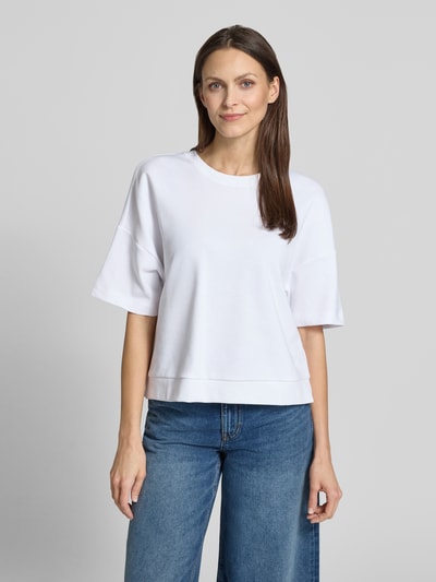 Kobieta nosi damski t-shirt z mieszanki bawełny o pudełkowym kroju, model 'Tilina' od JOOP!, okrągły dekolt, widok całej sylwetki z przodu