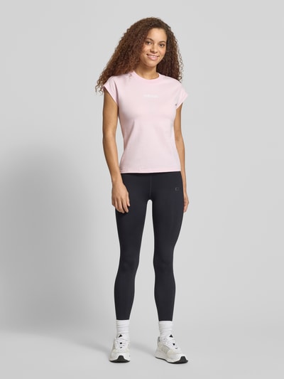 Frauenmodel trägt T-Shirt mit Rundhalsausschnitt von adidas Sportswear in Rosa, Reine Baumwolle, taillierte Passform, Label-Detail, Ganzkörperansicht von vorne. Rückenlänge bei Größe S: 57 cm.