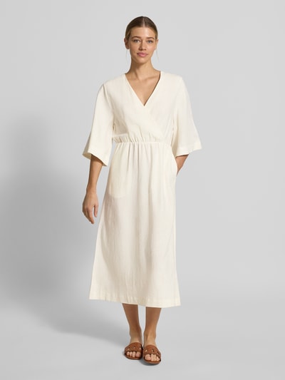 Frauenmodel trägt Midikleid aus Leinen-Mix mit Kimonoärmeln Modell 'Laura' von GUIDO MARIA KRETSCHMER WOMAN, cremefarben, taillierter Schnitt, V-Ausschnitt, Wickel-Optik, glatte Textur, Ganzkörperansicht von vorne.