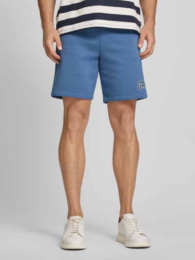 Männermodel trägt Sweatshorts mit Logo und elastischem Bund von GAP aus Baumwoll-Mix, Regular-Fit, Eingrifftaschen, Ganzkörperansicht von vorne.
