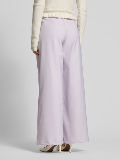 Vrouwenmodel draagt Wide Fit Stoffhose mit Bundfalten Modell 'Kate' van GUIDO MARIA KRETSCHMER WOMAN in lichtlila, productdetails zichtbaar, volledige lichaamsweergave achterkant.