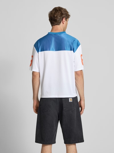 Männermodel trägt Trikot-Shirt mit Logo- und Motiv-Prints Modell 'OG Sport College' von KARL KANI, Boxy-Fit, Rückenlänge 64 cm, Ganzkörperansicht Rückansicht.