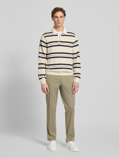 Männermodel trägt Regular Fit Hose mit Gesäßtaschen Modell 'Evans' von Brax aus beigem Baumwoll-Mix mit Stretch, Ganzkörperansicht von vorne.