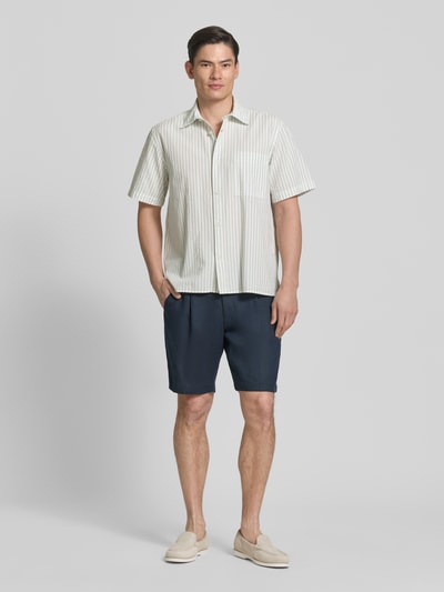 Männermodel trägt Relaxed Fit Freizeithemd aus reiner Baumwolle Modell 'STUART' von SELECTED HOMME mit Streifenmuster und Kentkragen, Ganzkörperansicht von vorne.