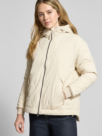 Vrouwenmodel draagt Gewatteerd jack met tweewegritssluiting van camel active, recht pasvorm, capuchon met tunnelkoord, steekzakken, elastische mouwboorden, ruglengte maat 36: 71 cm, schouderbreedte: 48 cm, borstwijdte: 56 cm, mouwlengte: 58 cm, geheelopname van voren.
