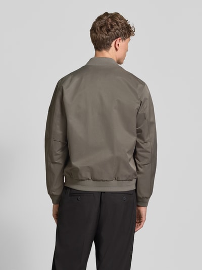 Männermodel trägt Regular Fit College-Jacke mit Baumwoll-Anteil von Marc O'Polo in einfarbigem Oliv, elastische Abschlüsse, Ganzkörperansicht Rückansicht.