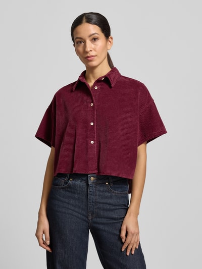 Frauenmodel trägt Cropped Hemdbluse mit Knopfleiste Modell 'PADOW' von American Vintage in Dunkelrot, lockerer Schnitt, reine Baumwolle, Hemdblusenkragen, 1/2-Ärmel, glatte Textur, Ganzkörperansicht von vorne.