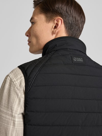 Männermodel trägt Steppweste mit Stehkragen und Reißverschlusstaschen von NAUTGÅRD, Regular-Fit, schwarze Farbe, Rückenansicht, Nahaufnahme Oberkörper. Rückenlänge 70 cm, Schulterbreite 34 cm, Brustweite 45 cm bei Größe M.