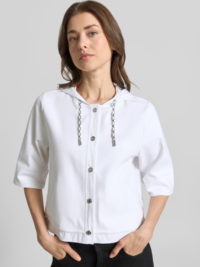 Frauenmodel trägt Regular Fit Jacke mit Kapuze von Marc Cain in Weiß, Halbarm, elastischer Baumwoll-Mix, Knopfleiste, Nahaufnahme Oberkörper.