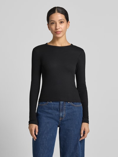 Frauenmodel trägt schwarzes Slim Fit Langarmshirt aus Baumwoll-Mix Modell 'CHLOE' von VERO MODA, kombiniert mit blauer Jeans, Ganzkörperansicht von vorne. Damen Langarmshirt von VERO MODA.