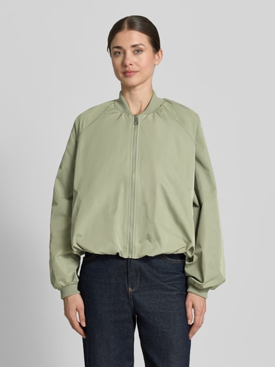 Frauenmodel trägt Blouson mit elastischen Ärmelabschlüssen und Reißverschluss von Zero, salbeigrün, Loose-Fit, Ganzkörperansicht von vorne, kurze Rückenlänge 52 cm, Schulterbreite 40 cm, Brustweite 50 cm, Ärmel 55 cm, Raglanärmel, Stehkragen, glatte Textur.