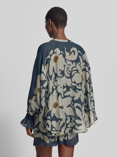 Männermodel trägt bluzka 'Bluse mit Schluppe und Volantärmeln' von Luisa Cerano, mieszanka lyocellu z dodatkiem ramii, krój loose fit, długość tyłu 74 cm, długość rękawów 65 cm, szerokie rękawy z marszczonym detalem, wzór w jasne i granatowe kwiatowe motywy, tekstura lekko przezroczysta, widok całej sylwetki z tyłu.