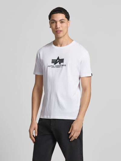 Männermodel trägt Herren T-Shirt aus Reine Baumwolle, Gerader-Schnitt, Modell 'BASIC' von Alpha Industries, Label-Details, Ganzkörperansicht von vorne.