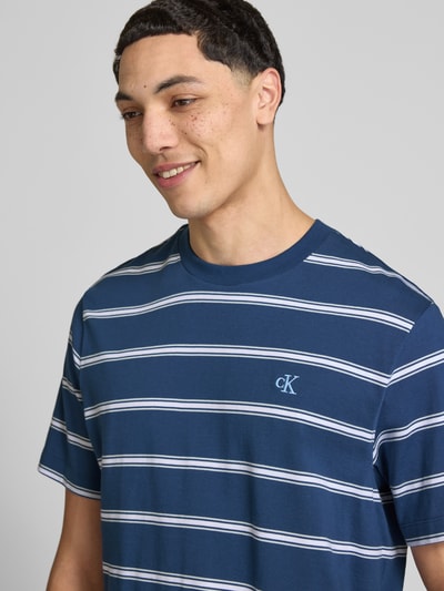 Männermodel trägt T-Shirt mit Logo-Stitching von Calvin Klein Jeans, Reine Baumwolle, Gerader-Schnitt, Rundhalsausschnitt, Nahaufnahme Oberkörper.