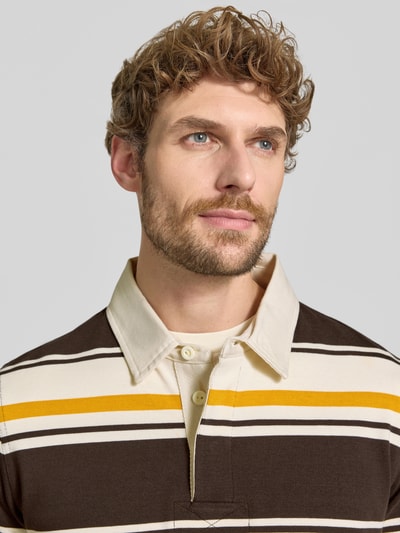 Mannenmodel draagt Regular Fit poloshirt uit puur katoen van GANT in bruin met gele en witte strepen, Nahaufnahme bovenlichaam.