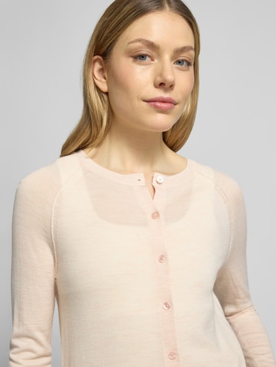 Frauenmodel trägt Regular Fit Strickjacke aus reiner Schurwolle Modell 'FONAMI' von BOSS in zartem Rosa, Feinstrick, Nahaufnahme Oberkörper.