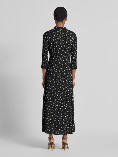 Frauenmodel trägt Maxikleid aus reiner Viskose Modell 'Savanna' von YAS mit floralem Allover-Print, taillierte Passform, dunkle Grundfarbe, 3/4-Arm, Ganzkörperansicht Rückansicht.