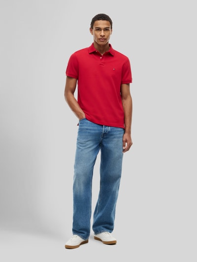 Männermodel trägt rotes Regular Fit Poloshirt aus Baumwoll-Mix von Tommy Hilfiger, kombiniert mit Jeans, Ganzkörperansicht von vorne. Herren Poloshirt.